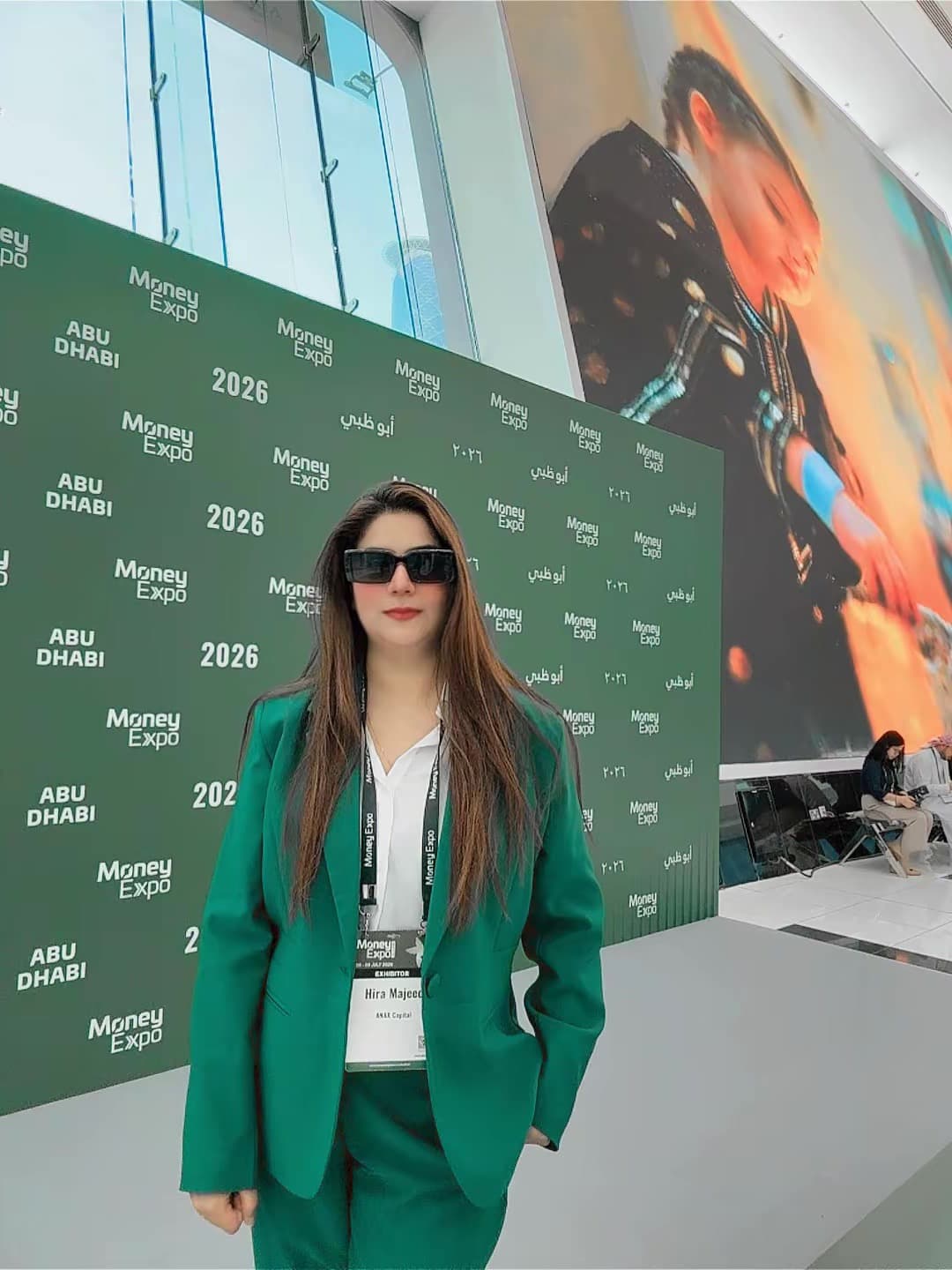 Hira Majeed in a green suit in front of the Money Expo Abu Dhabi 2026 branded wall
