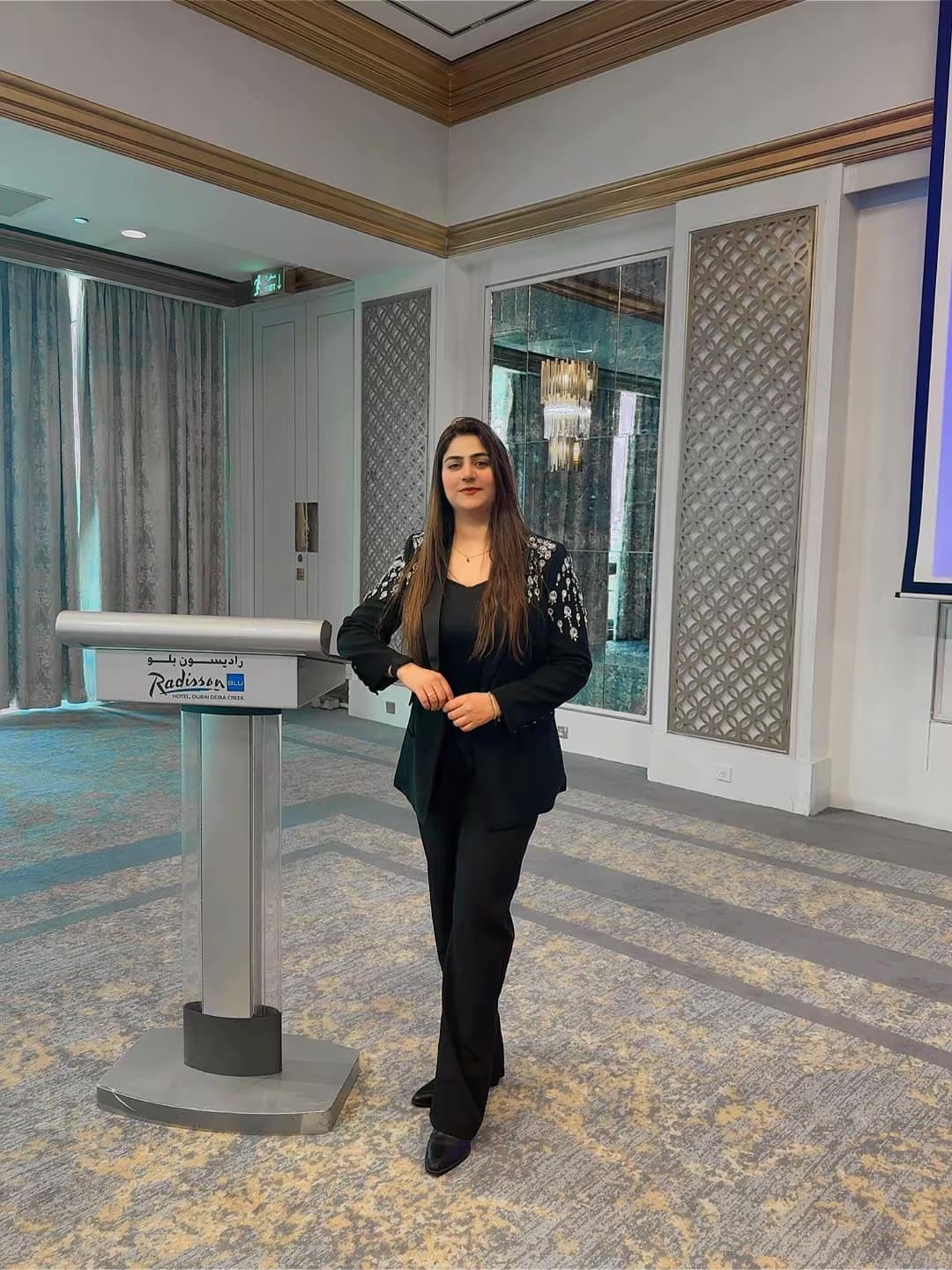 Hira Majeed standing beside a lectern in a hotel conference hall in Dubai